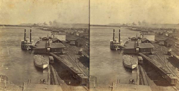 Elevated view of the sidewheel packet, <i>Keokuk</i>, at the Winona, Minnesota levee between 1858 and 1866. A barge and railway cars are in the foreground.