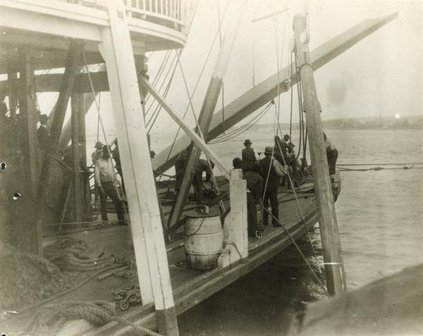 The sidewheel excursion, <i>Saint Paul</i>, after running aground near Muscatine. The spar is set and the line out. Dan Sauer, the carpenter, is holding the sounding pole. The sidewheel was later named the <i>Senator</i>.