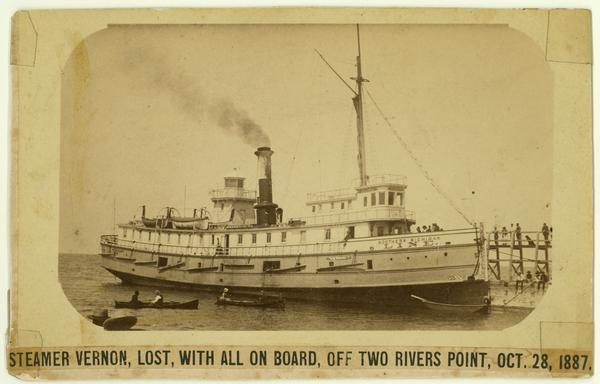 The screw passenger and freight vessel, "Vernon," docked, with several small boats in the foreground. This ship was lost with all on board off Two Rivers Point, Oct. 28, 1887.