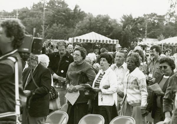Group of people listening to a speech at a labor day picnic.