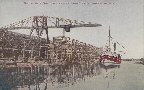 Colorized image of the frame of a large boat being built at the shipyards in Superior.