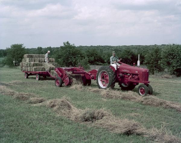 Color photograph of two men operating a Farmall 300 tractor and a McCormick baler in a field.