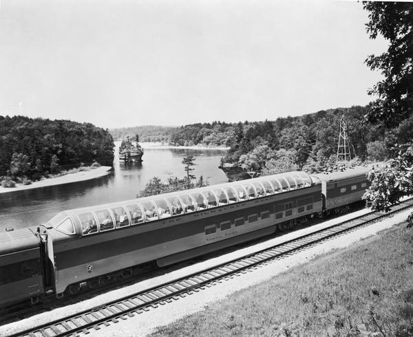 Exterior view of the Milwaukee Railroad superdome passenger car passing through the Wisconsin Dells.