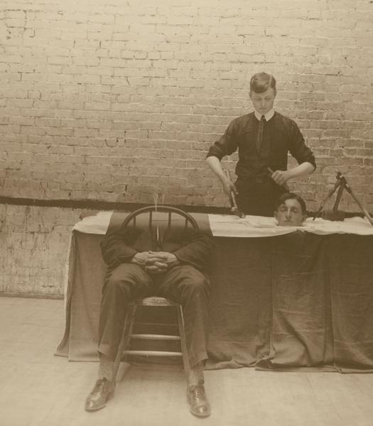 William C. Klatt, member of the Menomonie High School class of 1905, depicted as a physician operating on a disembodied head. Darkroom manipulation was used to create the illusion of the separation of the patient's head from his body.