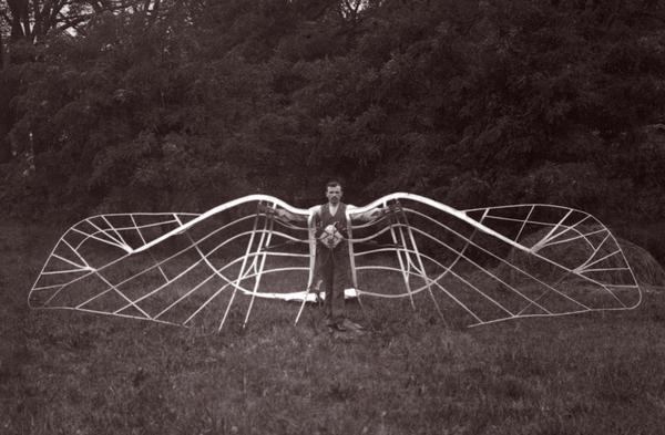 An unidentified man demonstrates his unsuccessful bird wing-like mechanism, which was part of an experiment in aviation.