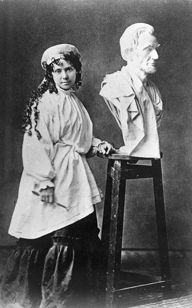 Vinnie Ream posing in her studio in Washington, beside her bust of Lincoln which had been brought from the White House after the assassination.
