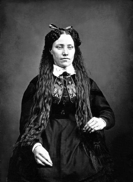 A portrait of a young woman in Norwegian costume, with long, loose hair and trimming at collar.