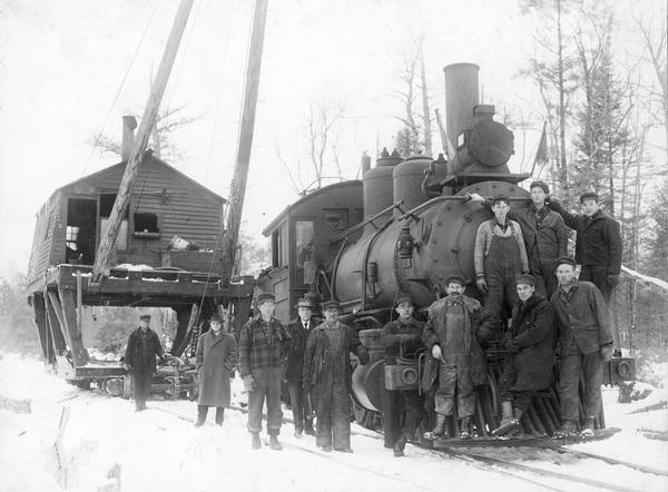 Taken on logging railroad, Lakeshore and Eastern Railroad, owned and operated by the Kneeland-McLurg Lumber company, Phillips, Wisconsin. Photograph is taken about 20 miles east of Phillips, in Emery Township.

This is locomotive number 80, serial number 1549, built by the Pittsburgh Locomotive Works (shipped April, 1895) for the Pittsburgh and Lake Erie Railroad. Number 80 was purchased by the John R. Davis Lumber Company in 1909, and in August 1912, the Davis Lumber Company, its logging railroad, and all equipment was sold to the Kneeland-McLurg Lumber Company. It was scrapped in 1932.

William Leiserson, second from left in photo, is investigating conditions in Wisconsin labor camps. He is posing with workers next to a logging locomotive and hoist. Fifth from left is Rudolf Kieble, Engineer, with the fireman and brakeman next to him.
