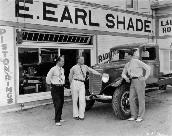 Three men standing next to an International truck outside the dealership of E. Earl Shade. Left to right are: C.W. Smallwood, Shade salesman, E. Earl Shade, and W.E. Johnson, motor truck blockman from the Baltimore motor truck branch.
