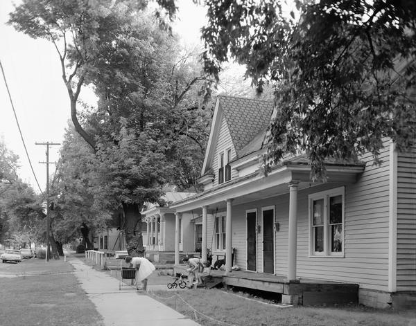 Old houses in a residential neighborhood with women and children at play.