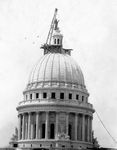 A crane places the gilded bronze statue, "Wisconsin," by Daniel Chester French, on top of the Wisconsin State Capitol dome.
