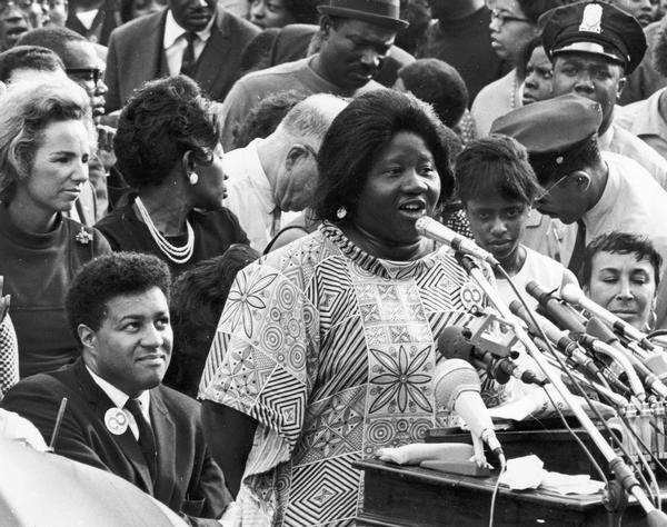 Johnnie Tillmon addressing a Mother's Day March on Washington, ca. 1968 or 1969. George Wiley is sitting directly behind her, on the left. Ethel Kennedy is looking on.