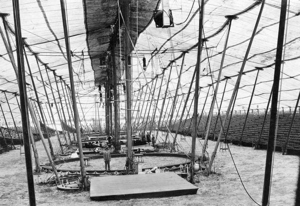 A view of the inside of a circus tent being readied for a performance.