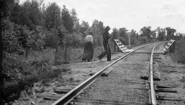 German farm couple returning from the fields, crossing railroad tracks.