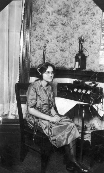 Ada Nye (Nemshoff) listening to a crystal radio set at the home of her aunt and uncle Ben and Ida Tovrog. Her cousin Lou Tovrog built the radio set.