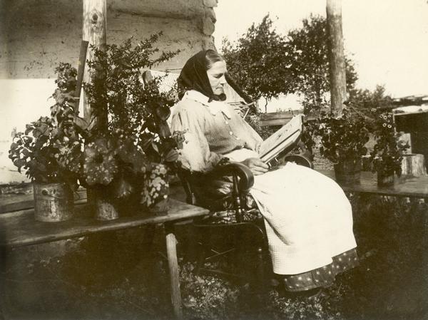 Woman reading the bible outdoors while seated in a chair.