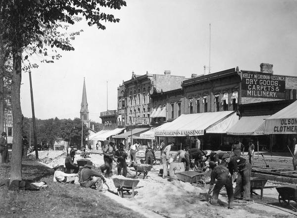 Construction crew building a double streetcar track around the Capitol Square on North Pinckney Street. The oversized awnings were common around the Square and along State Street.