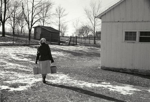 Edna Kern, wife of Ernest G. Kern, hauling water in buckets to the hen house.