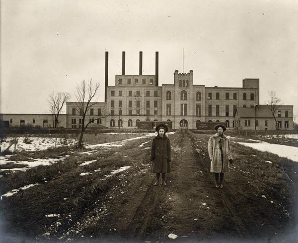 Two women standing on path in front of the Garver Feed Mill, which was originally a sugar beet processing factory.