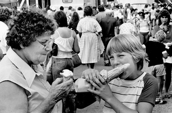 Bertha Hynek of Allenton is eating an ice cream cone while her grandson, Wesley Priesgen, 10, works on an ear of roasted corn.