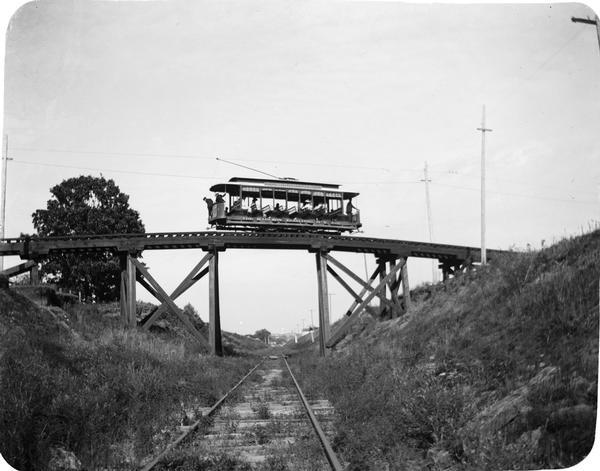 Rail car passing over the Harrison Street viaduct on the Wingra Park line. The line served the growing suburbs of University Heights, Oakland Heights, and Wingra Park. This car had ten bench seats running across the car and was rated as a fifty-passenger car. Such cars were extensively used for tranporting huge crowds back and forth to the circus grounds and for refreshing  summer rides.