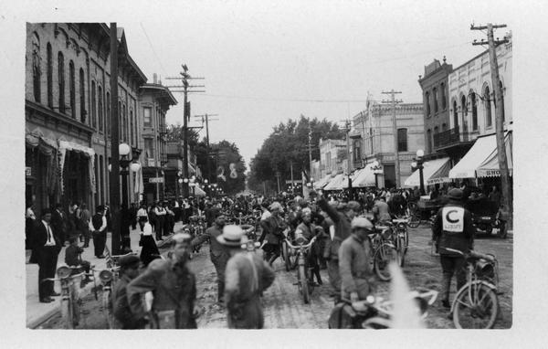 A crowd of people in the street, many of them with motorcycles, possibly getting ready to race.