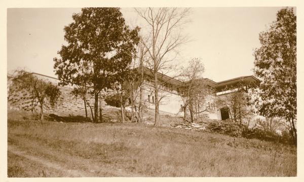 Southeast elevation of Taliesin, the home of Frank Lloyd Wright, probably during construction. The view includes the bedroom wing and covered terrace, as well as basement windows and a large opening in the basement under the terrace. Taliesin is located in the vicinity of Spring Green, Wisconsin.