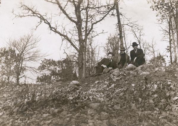 View looking up towards Reverend F.M. Gilmore, Professor W.E. Leonard, and Charles Brown relaxing on a burial mound on Fox Bluff near Lake Mendota.