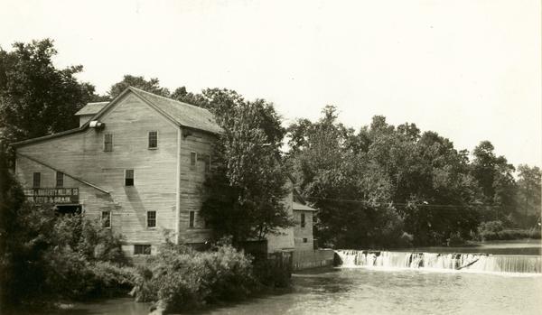 A large building, possibly a mill, next to a river.