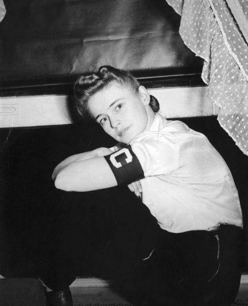 Dickey Chapelle seated by an open window, wearing the correspondent arm band. Taken at time of her first recognition by the War Department as <i>Look's</i> photographer.