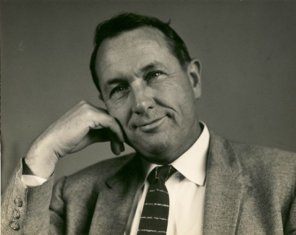 Head and shoulders portrait of Myles Horton smiling and leaning his cheek against his hand.