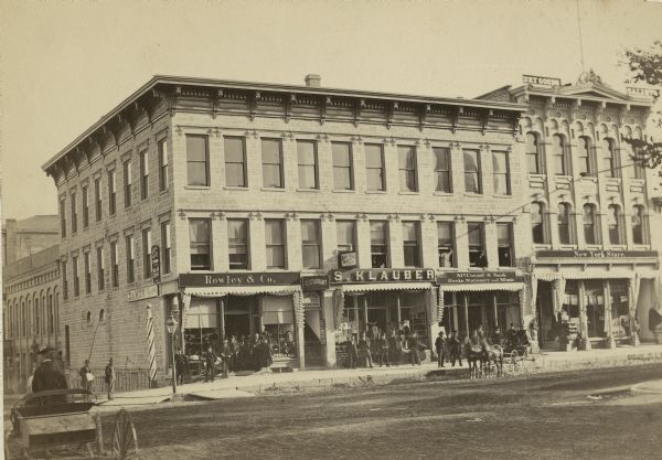 The S.S. Kresge Company building at 25-27 East Main Street. Several businesses, including Rowley & Co., a general store, and S. Klauber dry goods, are in this building. There is a Ladies Oyster Parlor and a billiard hall upstairs. McConnell and Smith, selling books, stationery and music was on the ground floor. Outside, there is a woman in a buggy, at tall striped barber pole, a gas lamp, and high curbing with dirt roads.

The building was built by J.C. Fairchild. It was occupied by S.S. Kresge Company located at 27 E. Main Street for many years.