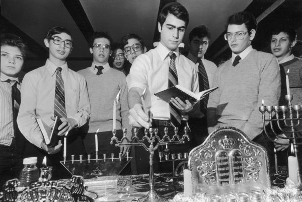 Hanukkah Ceremony - Abraham Anton uses a servant candle, called the Shamas, to light the first candle of Hanukkah Tuesday night as fellow students watch at the Wisconsin Institute for Torah Study, 3288 N. Lake Drive. The Shamas may become the center candle or the top candle, depending on the style of the Menorah. Hanukkah, an eight-day Jewish festival, commemorates a miracle that occurred when a one-day supply of oil lasted eight days after Judas Maccabeus recaptured the temple at Jerusalem.