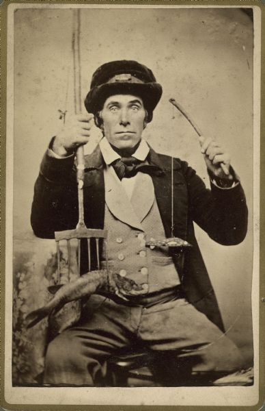 Studio portrait of a fisherman with his lure, spear, and catch.