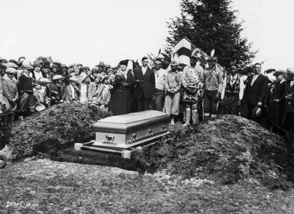 A group of people pose around the casket containing the body of Chief Simon Onanguisse Kahquados at Peninsula State Park during a reburial ceremony.