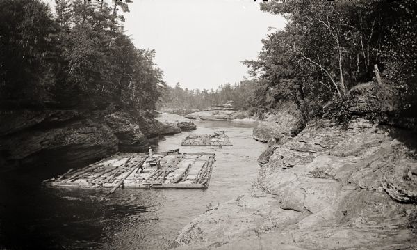 Two lumber rafts with men aboard floating down the Wisconsin River.