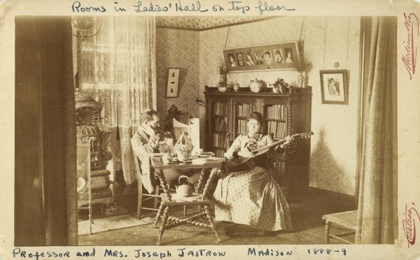 Professor Joseph Jastrow reading, and Rachel Jastrow playing guitar in a room on the top floor of Ladies' Hall (later Chadbourne Hall, razed 1957), in Madison, 1888-89.
