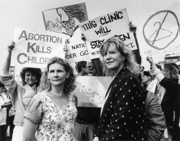 Pro-Choice and Pro-Life Leaders Maggi Cage (right), a pro-choice leader, and Janel Parshall (left), a pro-life Wisconsin advocate, stand in front of a crowd of protesters at a reproductive rights rally. Cage owned an abortion clinic in Appleton, WI, for 20 years.