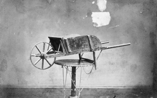 Boy's wheelbarrow, produced at children's carriage factory, displayed on a table.