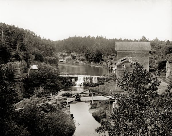 Mirror Lake Mill Elevated view of Mirror Lake Mill with bridge in foreground. Two women are standing on the bridge looking down at the river.