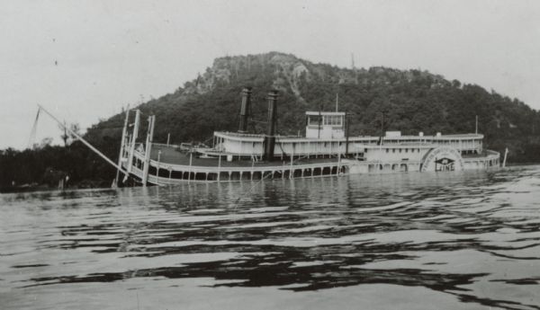 Side view of the sidewheel packet, <i>Quincy</i>, sinking in 1906. Only her two upper decks are above water. Trempealeau Mountain is in the background. Later renamed the <i>J.S.</i>