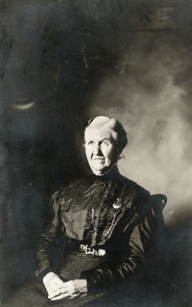 Studio portrait of Susan Washburn, who is wearing a black dress and a watch on a chain.