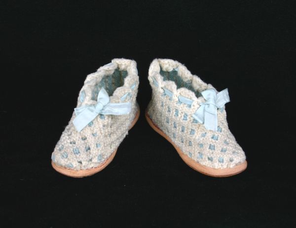 Child's slippers, with ribbon ties, knitted of ecru and blue wool yarn.