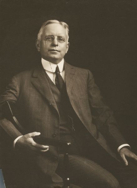 Studio portrait of Richard Ely seated in a chair wearing a suit and pince-nez.