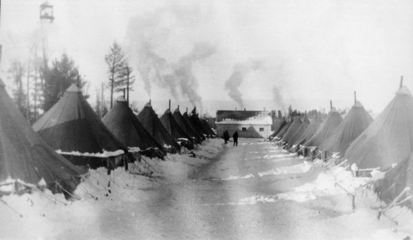 Winter view of the Civilian Conservation Corps (CCC) Camp Beaver tents with two men in the background. CCC Company 1604 used Camp Beaver as their base camp until 1935.