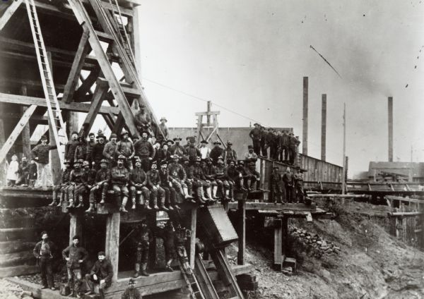 Group of miners posed on a platform near an iron mine.