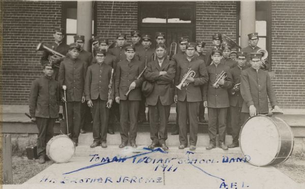 Group portrait of the Tomah Indian School Band in uniform, holding their instruments.