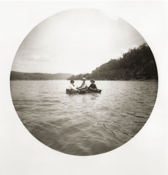 Three boys in a crude boat on the Monongahela River.