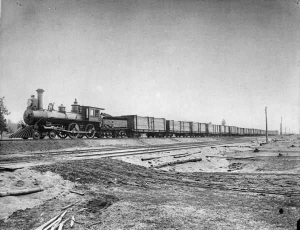 A Wisconsin Central Railroad locomotive with Engine #42 hauling lumber from Antigo Lumber Company.