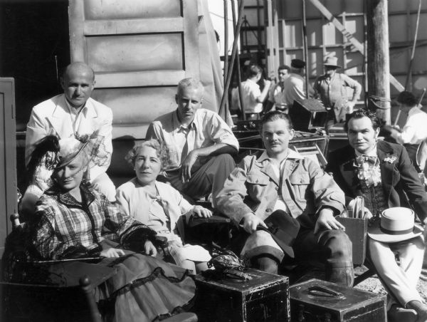 The cast of <i>Barbary Coast</i> pose on the set. In the back from left to right are: Samuel Goldwyn and Howard Hawks. In front from left to right are Miriam Hopkins, Edna Ferber, an unidentified actor, and Edward G. Robinson.